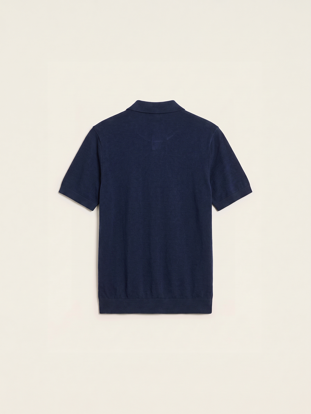 #blue-navy_group A navy blue short-sleeve knit polo shirt shown from the back, centered on a light cream background.