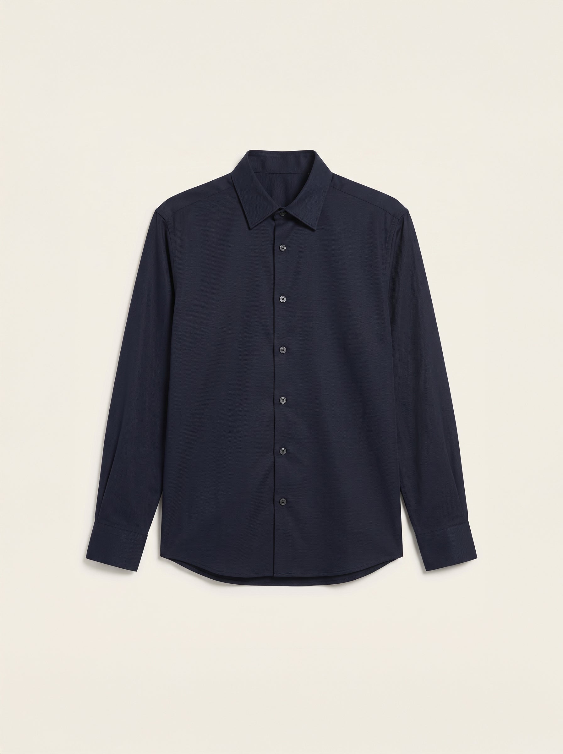 #Blue-Navy_group A dark navy blue long-sleeve button-up shirt with a classic collar, laid flat against a light beige background.