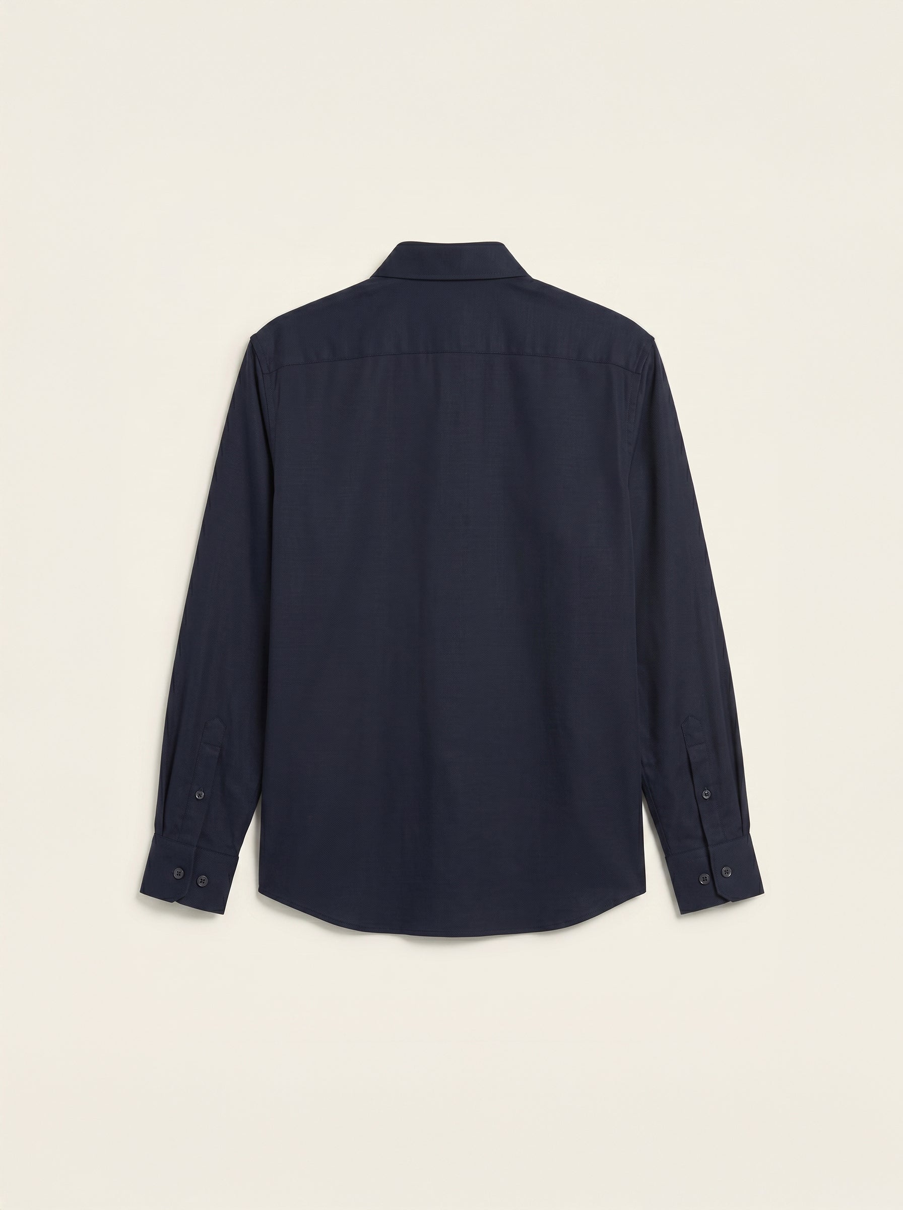 #Blue-Navy_group A dark navy blue long-sleeve button-up shirt shown from the back, laid flat against a light cream background.
