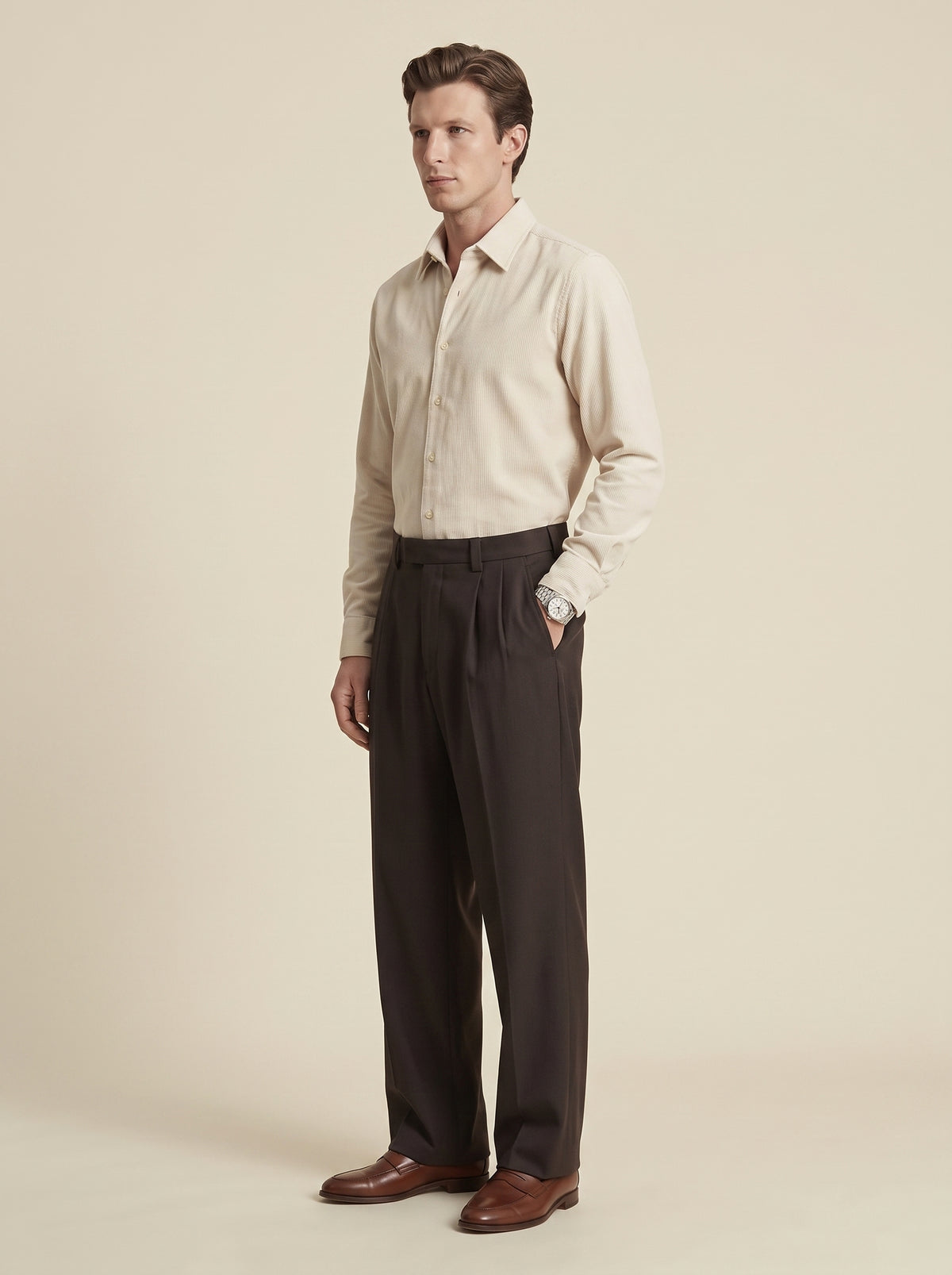 #Cedar-Brown_group A man modeling a light beige long-sleeve button-down shirt and dark brown pleated trousers, paired with brown leather dress shoes, against a solid beige studio background.