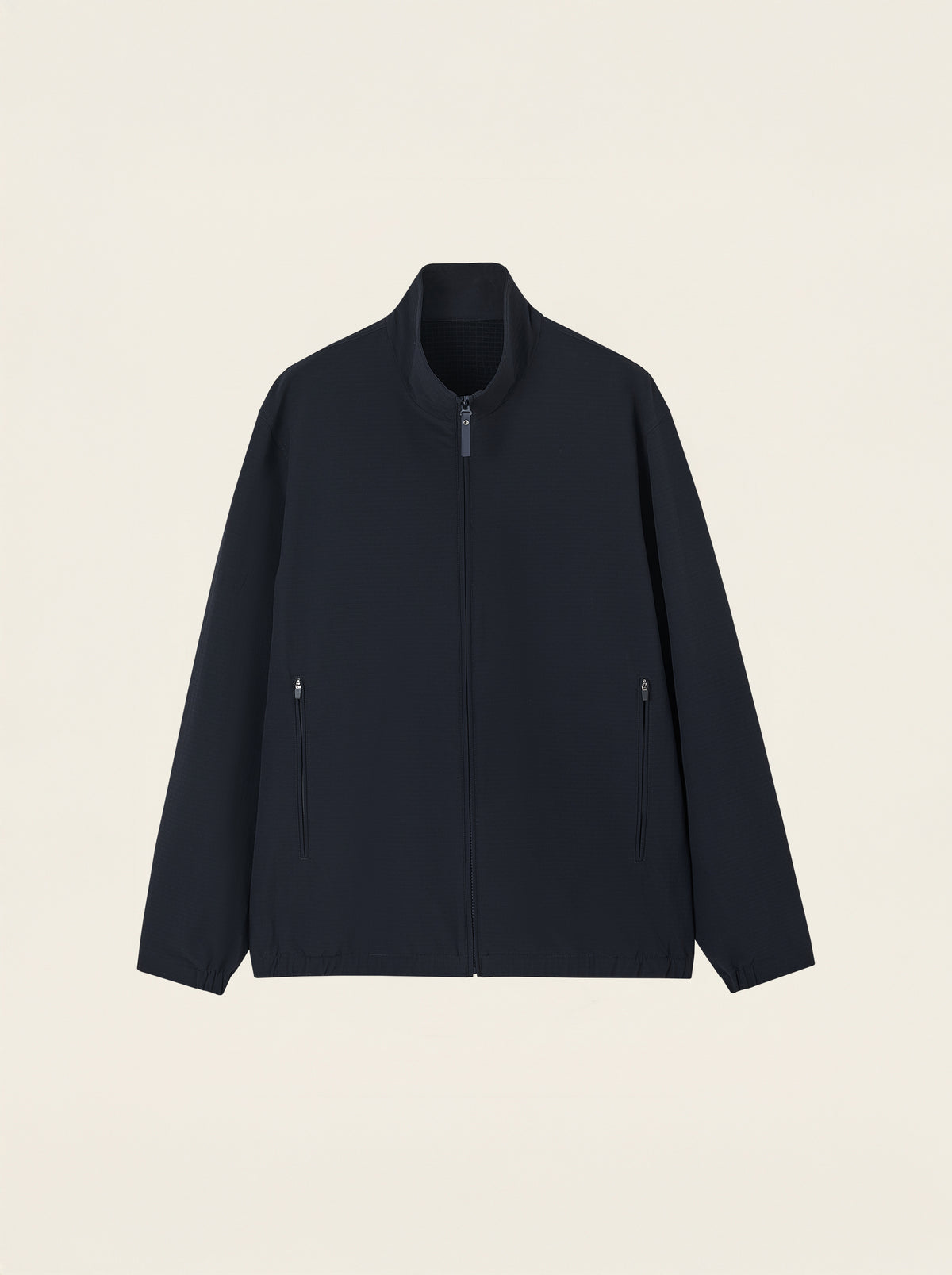 #Blue-Navy_group A dark navy blue zip-up jacket with a stand-up collar and zippered hand pockets, displayed flat against a light cream background.