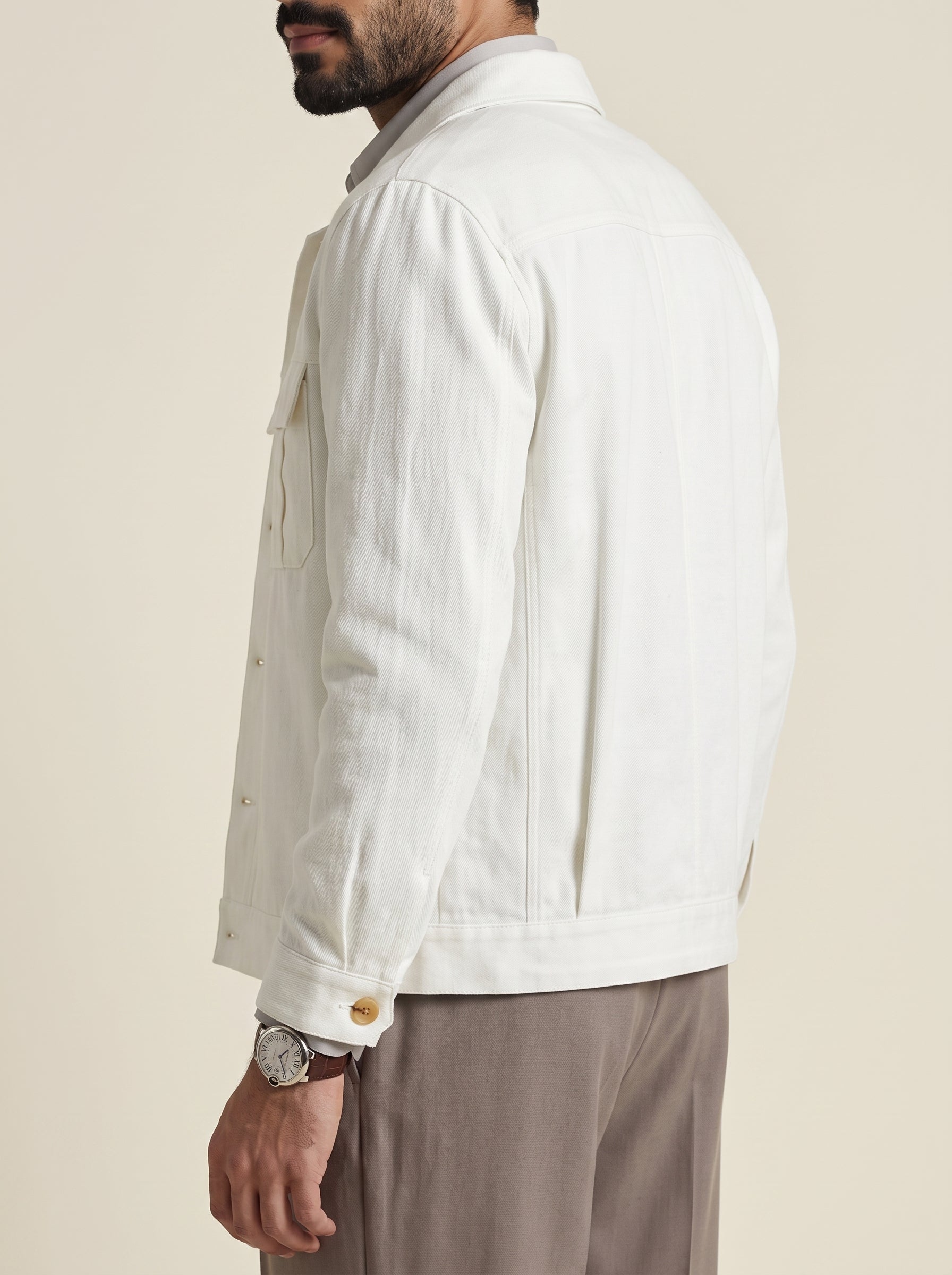 #Pure-White_group A man wearing a white linen jacket, shown from a side-back angle against a solid beige background.