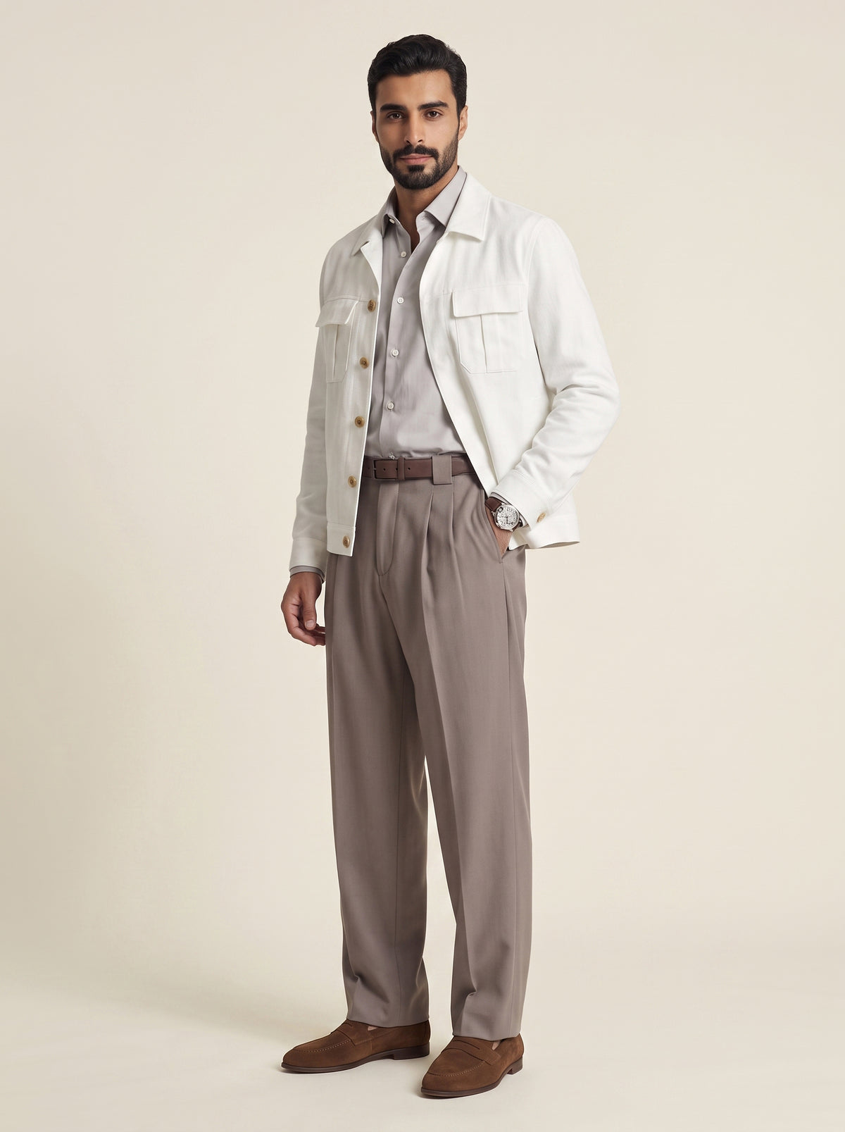 #Pure-White_group A man modeling a light cream denim jacket over a light gray button-down shirt, paired with taupe pleated trousers and brown suede loafers, against a solid beige studio background.