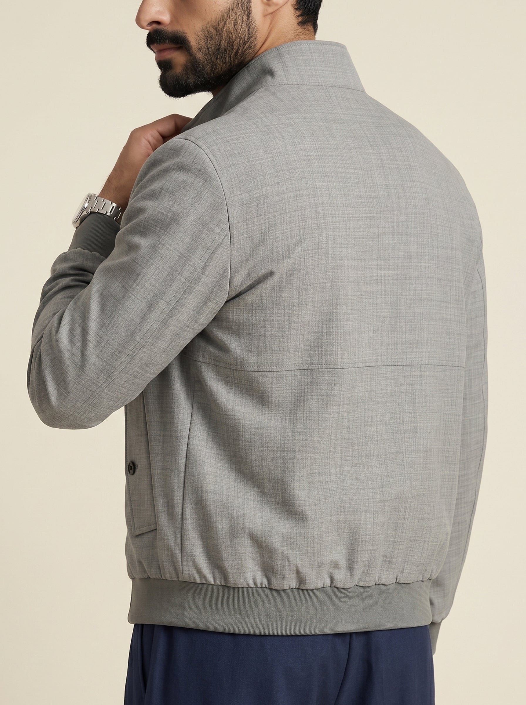 #Charcoal-Grey_group A man wearing a light gray textured jacket, shown from the back and side, with a beige background.