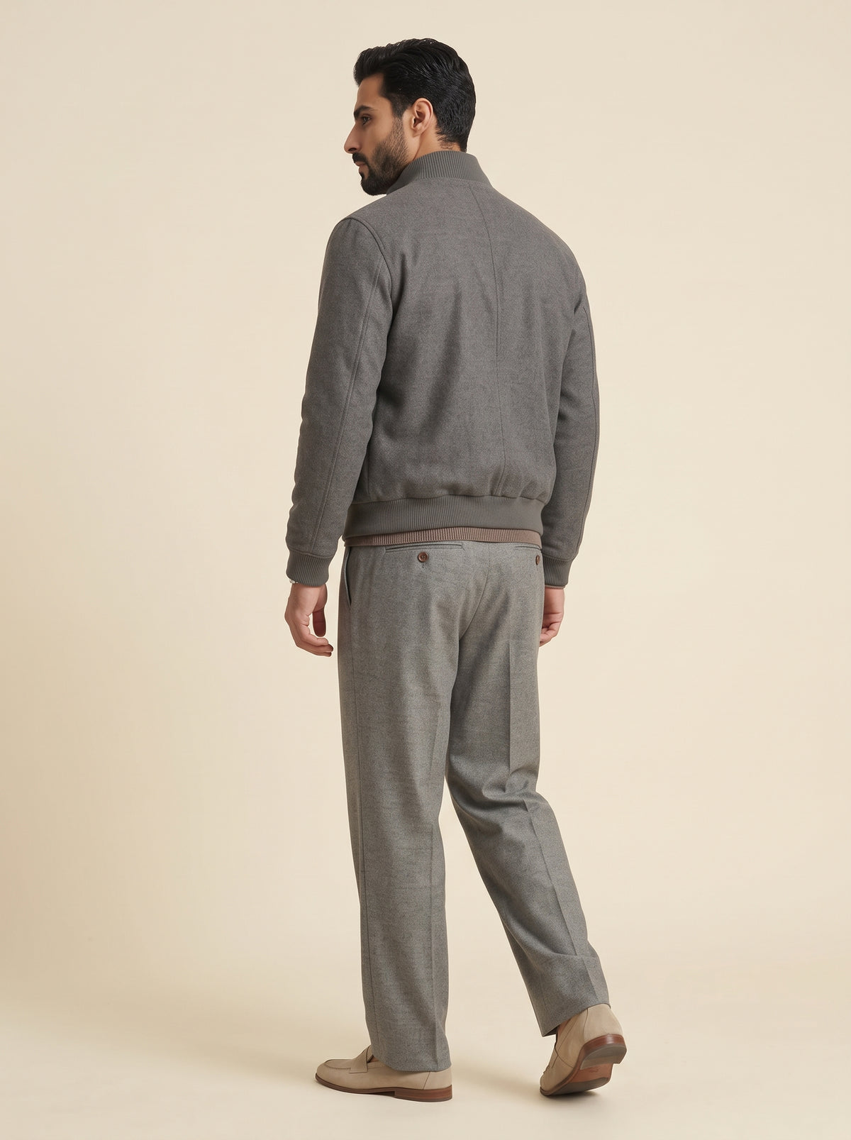 #Charcoal-Grey_group A man shown from the back wearing a gray zip-up jacket and matching gray trousers, standing against a plain beige studio background.