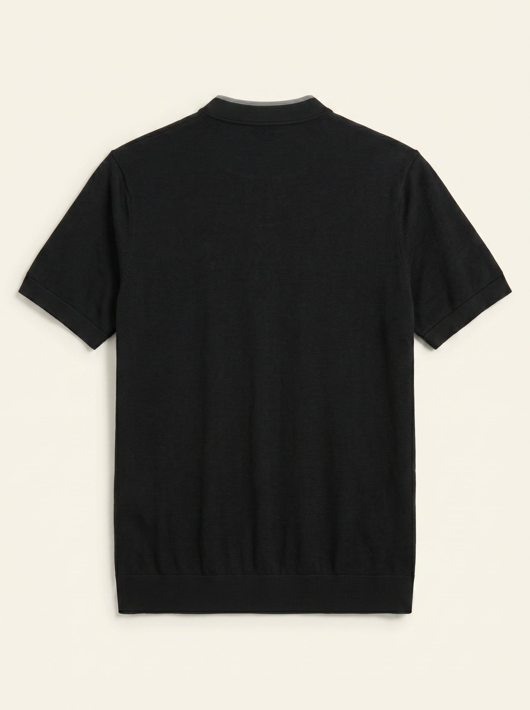 #Jet-Black_group A black short-sleeve knit polo shirt shown from the back, laid flat against a light cream background.