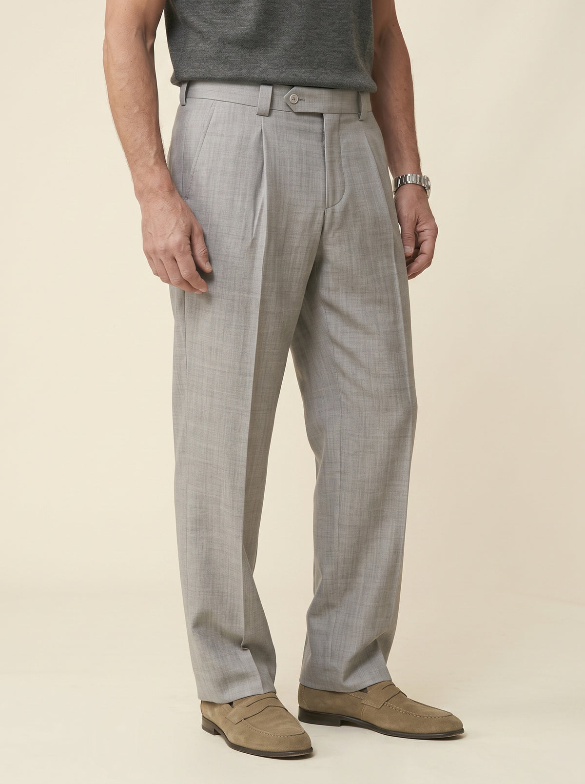 #Silver-Grey_group A man wearing light gray plaid dress pants, a dark gray t-shirt, and tan suede loafers, standing against a solid beige studio background.